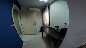 A room with a desk, a chair, a door, and a window with curtains. - Data Maisonettes and More (Chios)