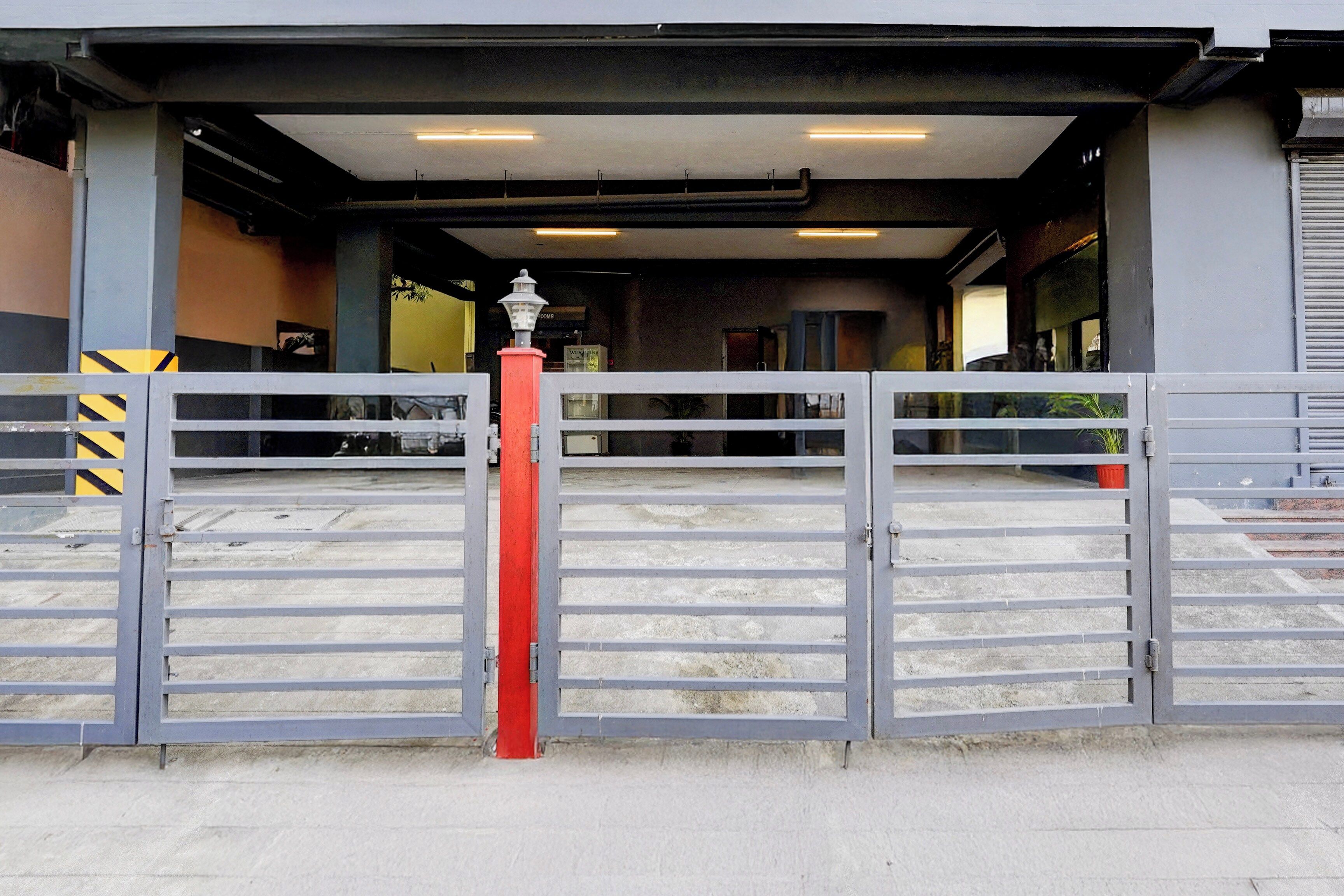 Una entrada protegida por un portón metálico y un poste rojo.