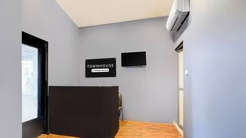 Zona de recepción de un hotel con un mostrador negro, un cartel que indica que es una casa de campo con servicios de empresa, y un televisor de pantalla plana montado en la pared.