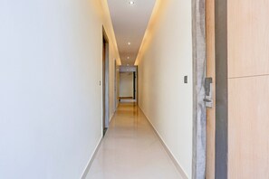 Un largo pasillo estrecho con piso y paredes de color claro, que conduce a una puerta al final.