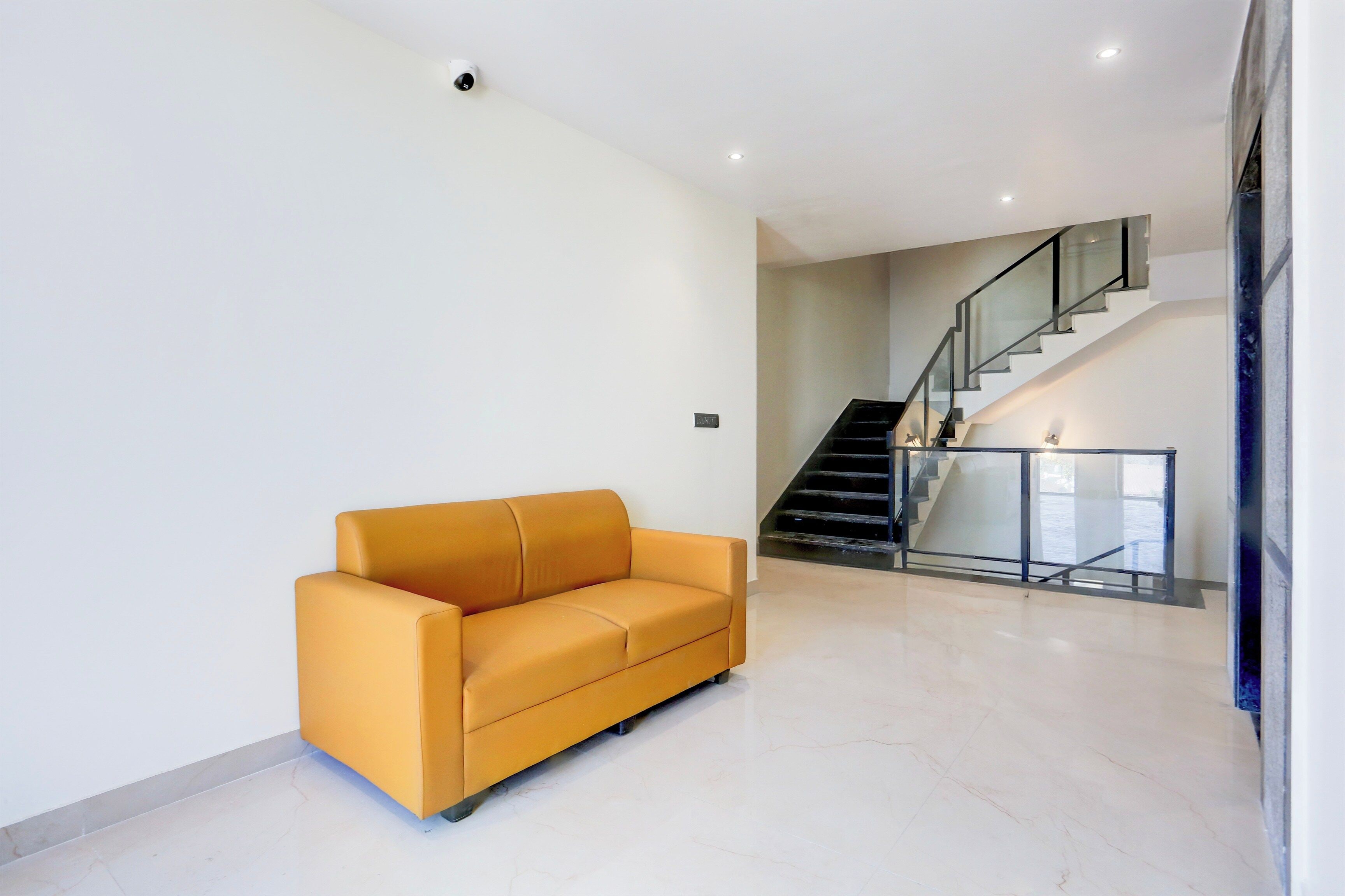 Een modern interieur met een bank, een trap en een glazen balustrade.