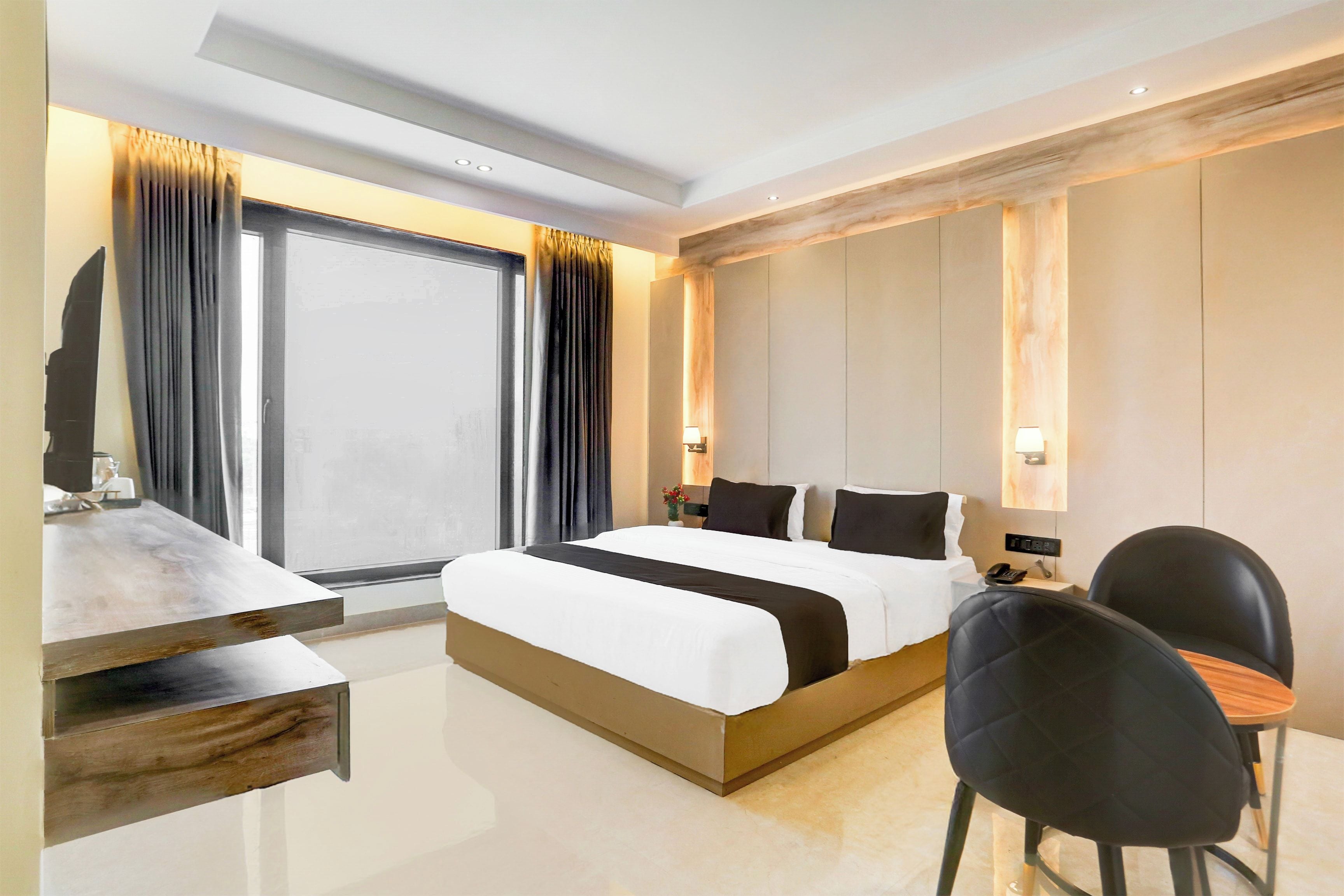 A modern hotel room with a large bed, bedside tables, a desk, and a chair.