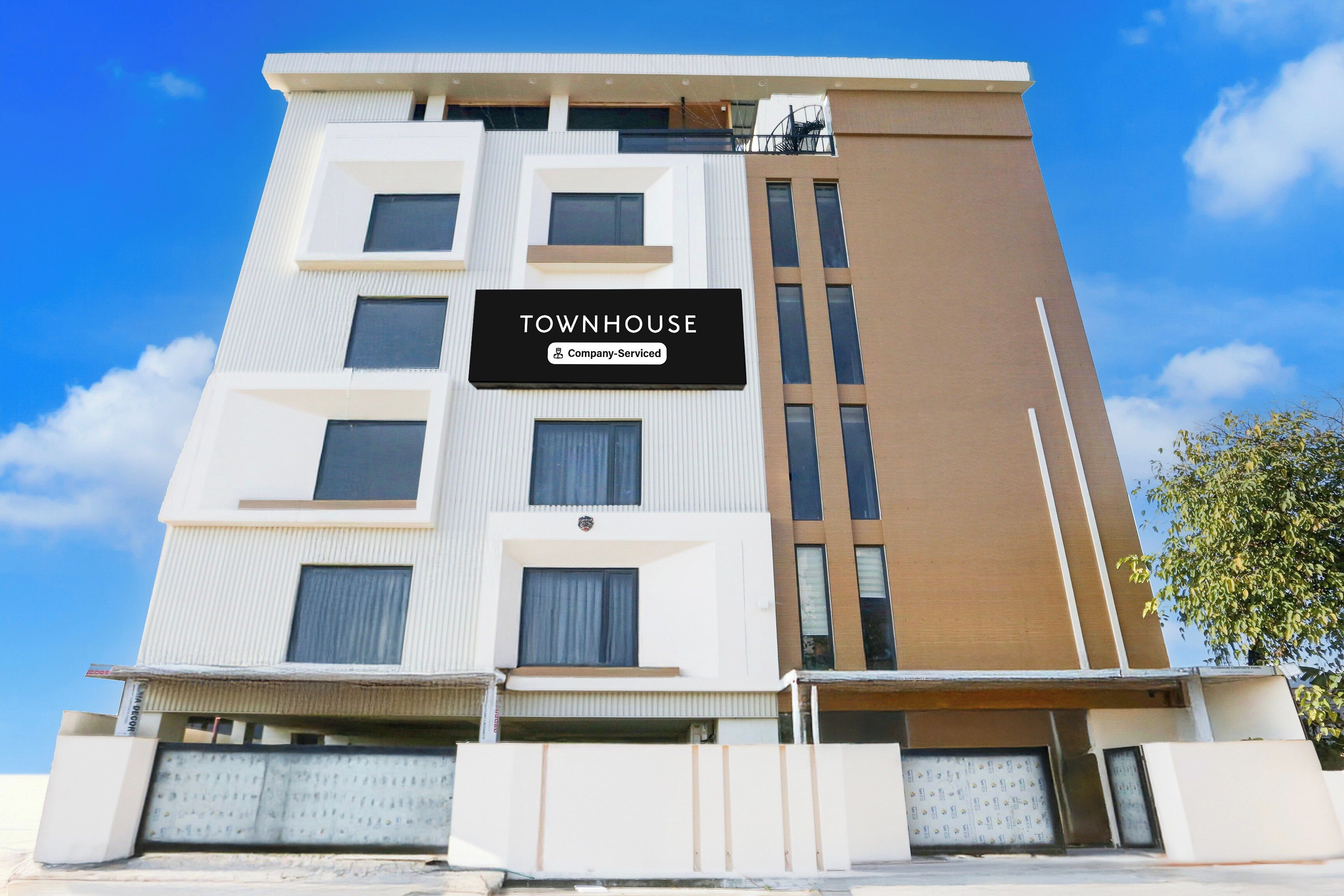 Un edificio de varios pisos con un letrero que dice 'TOWNHOUSE Company-Serviced'.
