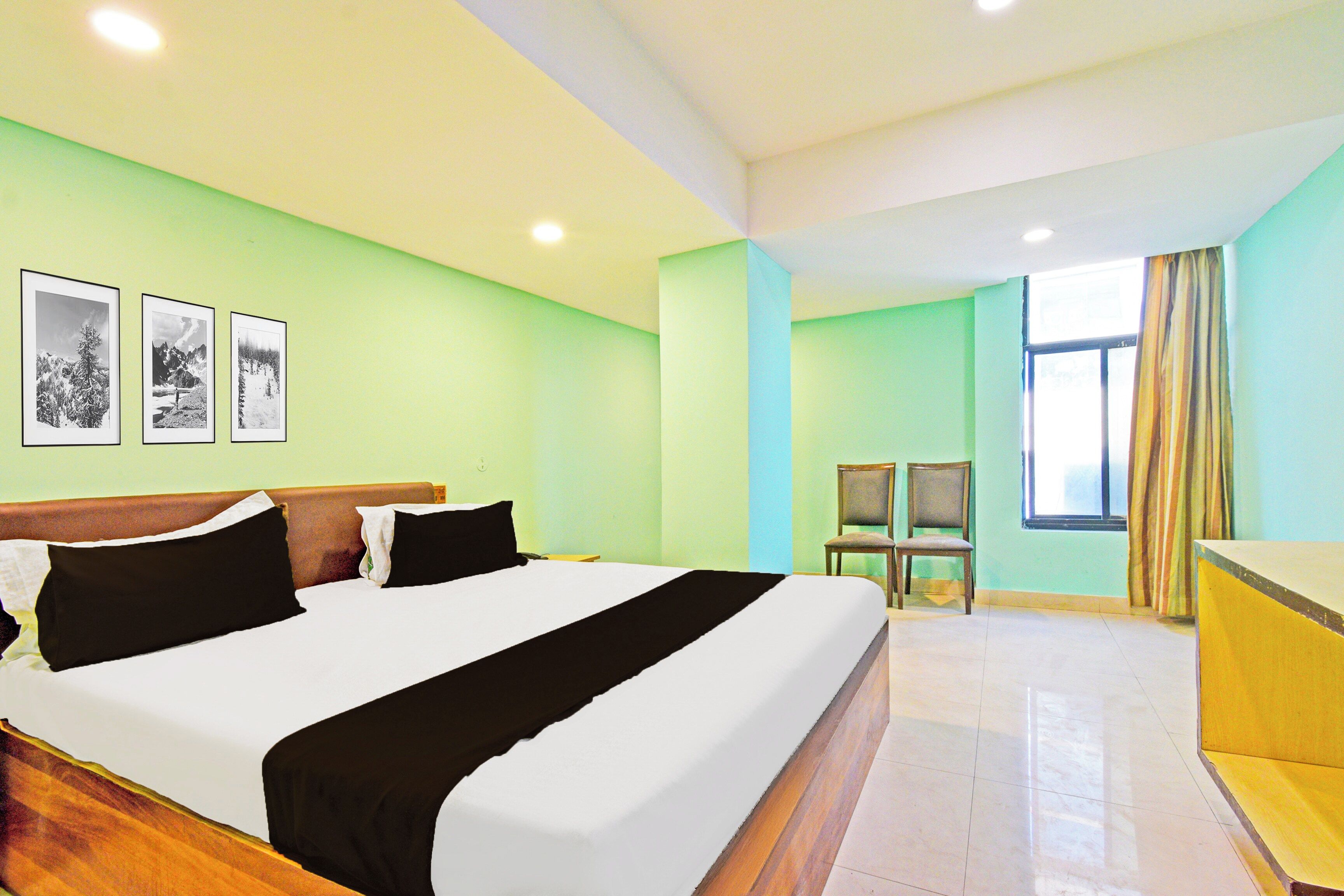 Una habitación de hotel con cama, una silla, un escritorio y un ventanal con cortinas.