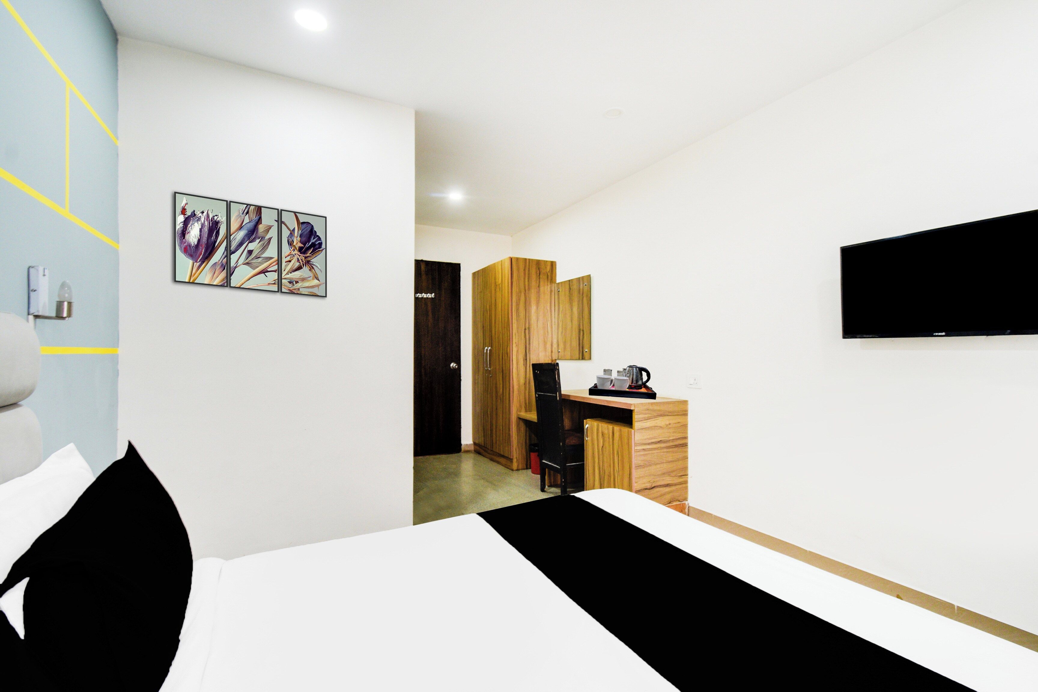 Habitació d'hotel moderna amb un llit, escriptori amb cafetera, televisió i un quadre a la paret.