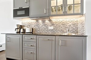 A modern kitchen with grey cabinetry, a stainless steel range hood, and a patterned backsplash. - Holiday apartment in Sylt with 1 bedroom (Westerland\/Sylt)