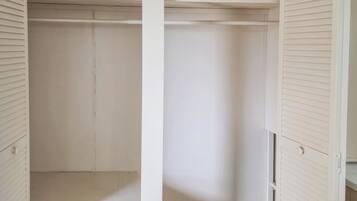 Un armario blanco con puertas correderas, un grifo de agua visible y un piso con baldosas.