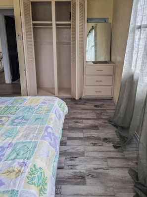 A bedroom with a bed, a wardrobe, a mirror, and a window with curtains. - Home Away From Home (Arnos Vale)