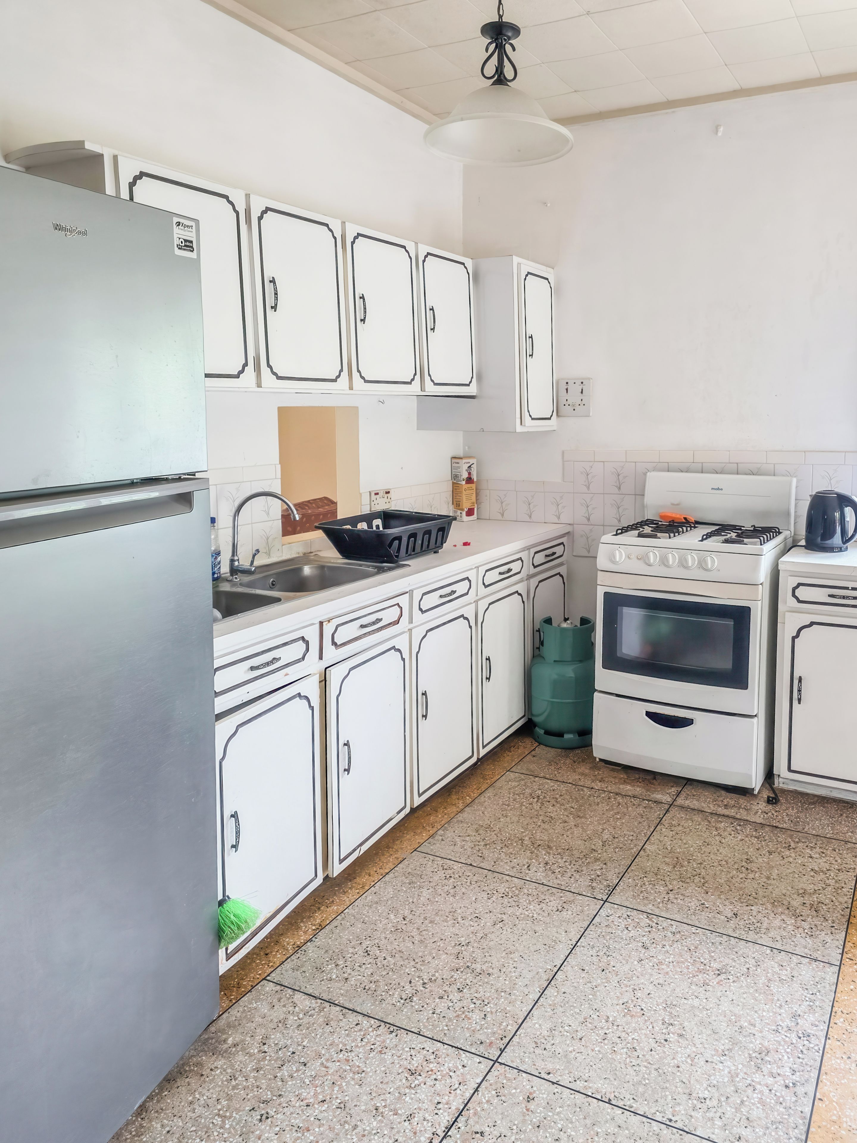 A kitchen with white cabinets, a refrigerator, a stove, and a sink.