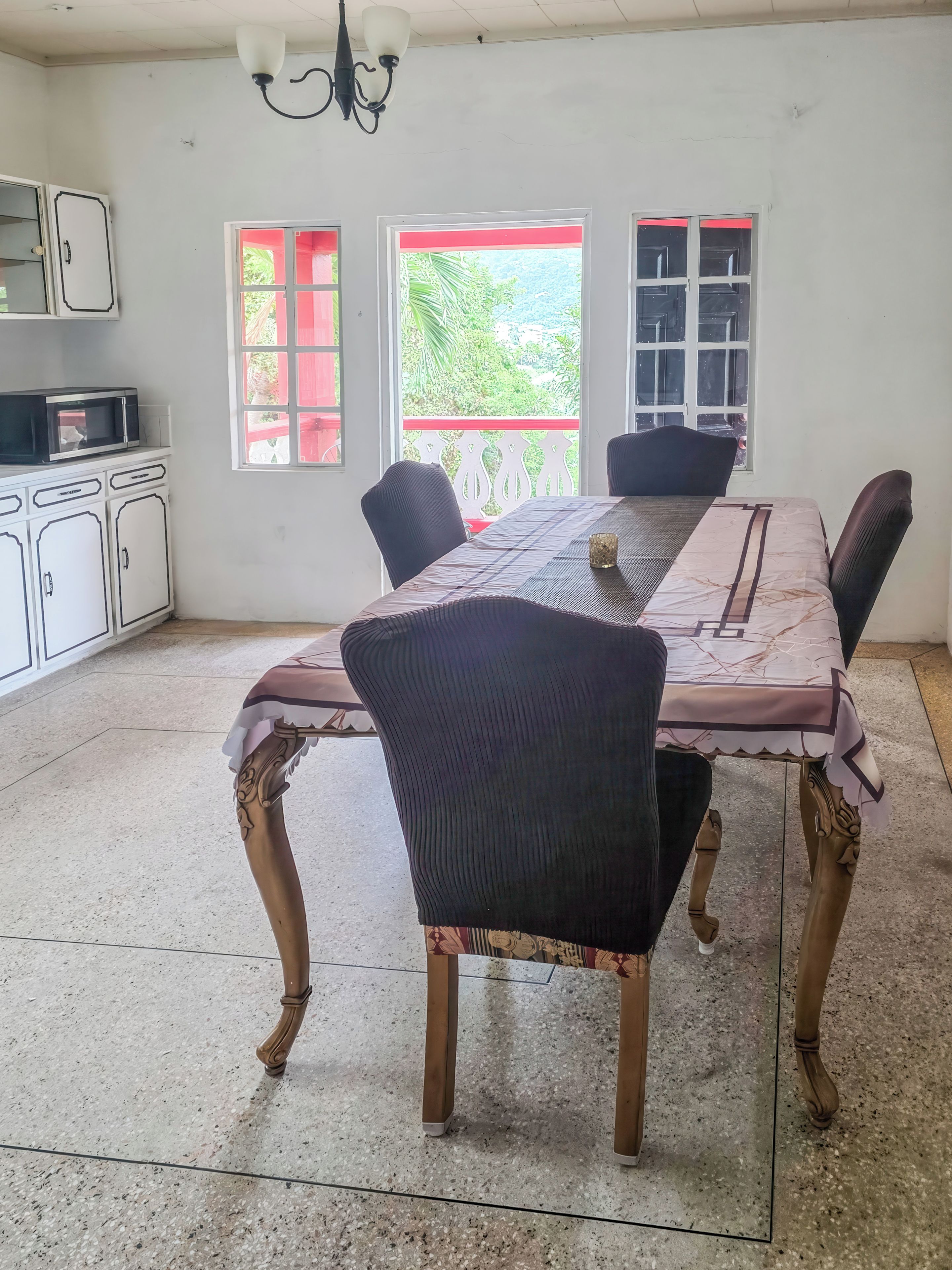 A dining area with a table, chairs, and a microwave on a cabinet.