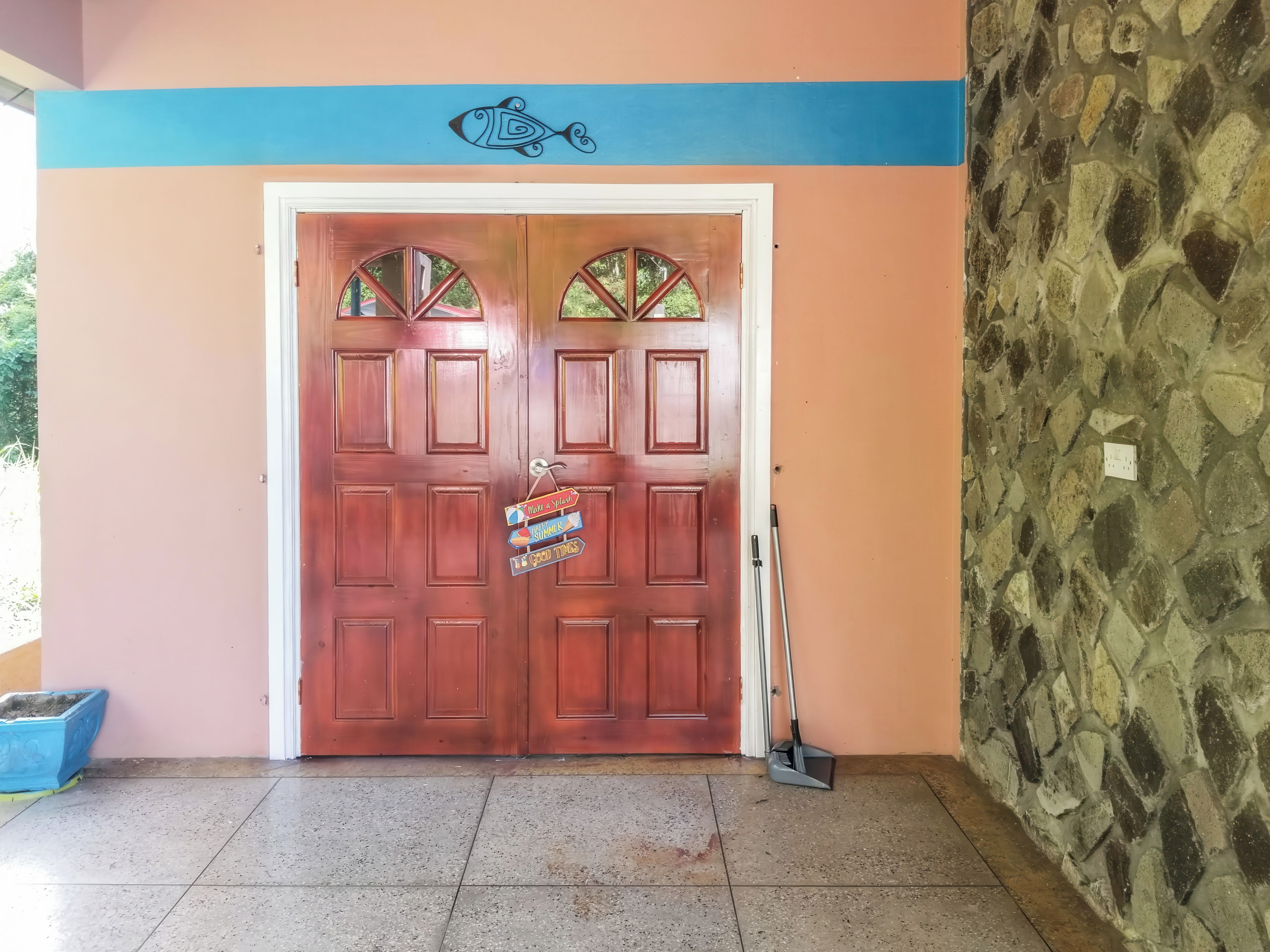 A wooden door with a sign, a stone wall, and a broom leaning against it.