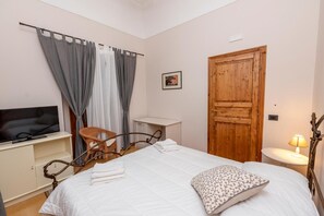Une chambre à coucher avec un lit, un téléviseur, une porte en bois, une chaise et un bureau.