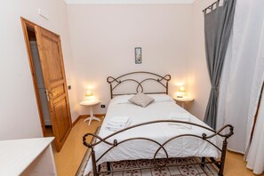 A small, neatly arranged bedroom with a single bed, bedside lamps, a wooden door, and a small table. - Villa 'Tecla' with Sea View (Capri Leone)