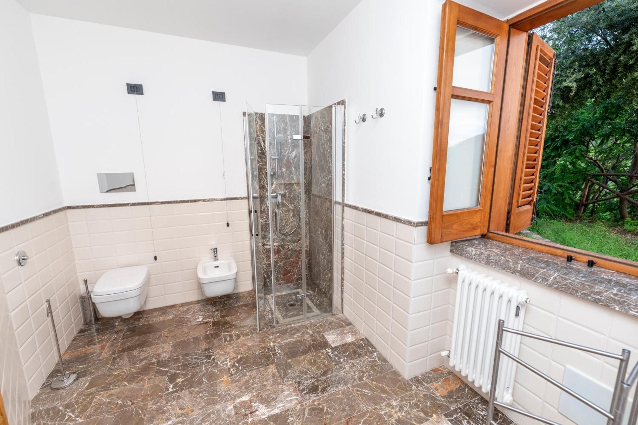 A bathroom with a shower, toilet, and bidet.