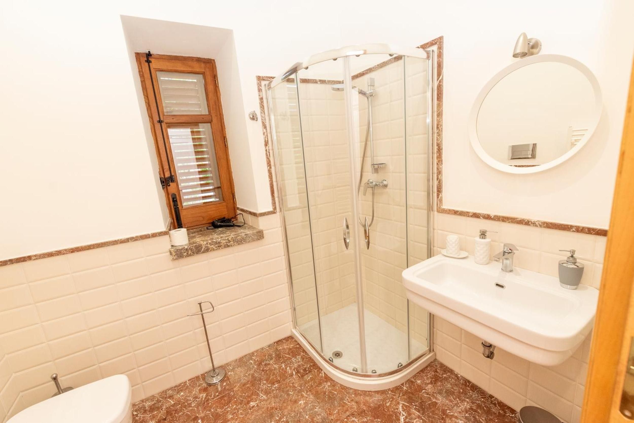 Un baño con ducha acristalada, lavabo con espejo e inodoro.