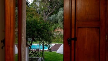 A wooden door leading to a backyard with a swimming pool and a paved area.