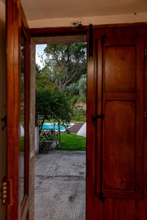 A wooden door leading to a backyard with a swimming pool and a paved area.