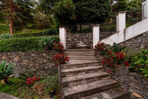 A stone staircase leading up to a white building, surrounded by greenery and red flowers. - Villa 'Tecla' with Sea View (Capri Leone)