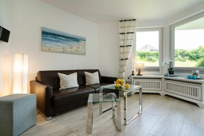 Uma sala de estar moderna com um sofá de couro, uma mesa de centro de vidro e uma pintura de uma cena de praia.