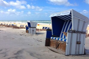 Beach chairs with a blue and white striped pattern, numbered 706, on a sandy beach with the ocean in the background. - Holiday apartment with 2 bedrooms (Westerland - Sylt)