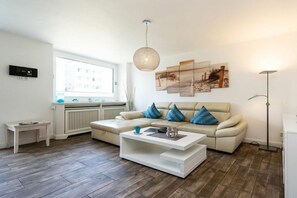 A modern living room with a sofa, coffee table, and artwork on the wall. - Sylt Residence Apartment 5 (Sylt Ortsteil Westerland)