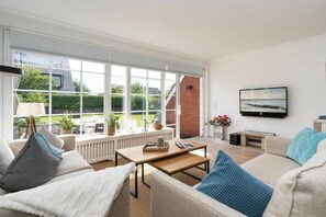 A modern living room with a sofa, coffee table, and a television on the wall. - Ostertresker Sea Garden (Tinnum - Sylt)