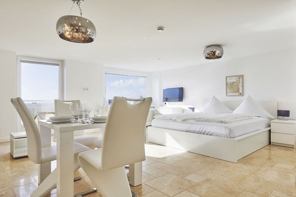 Un dormitorio moderno con cama, mesitas de noche y televisor.