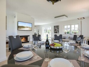 Un comedor con chimenea, televisor montado en la pared y un amplio ventanal que proporciona luz natural.