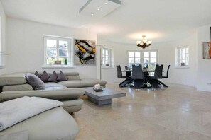 A spacious living room with a modern sofa, a dining table with chairs, and artwork on the walls. - Holiday home in Rantum with swimming pool (Rantum)