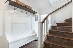 A staircase with a wooden handrail and a white wall with a shelf above it. - Holiday home in Sylt with swimming pool (Sylt)