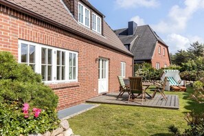 A brick house with a wooden deck and outdoor furniture. - Holiday apartment in Sylt with 2 bedrooms (Sylt Westerland)