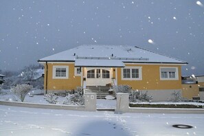 A two-story house with a snow-covered roof and a front porch. - Holiday apartment with 2 bedrooms (Strullendorf)