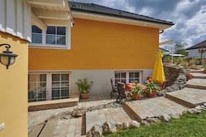 A yellow building with a patio area, outdoor seating, and potted plants. - Holiday apartment with 2 bedrooms (Strullendorf)
