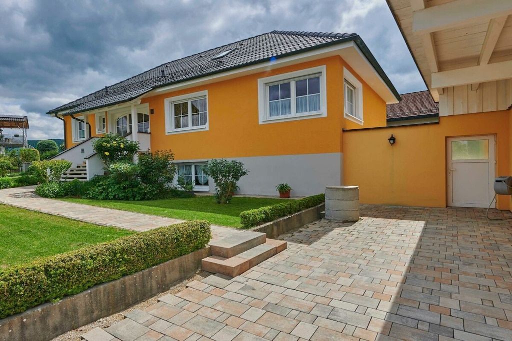 Een huis met twee verdiepingen, een betegeld dak, een verharde oprit en een verzorgd gazon.