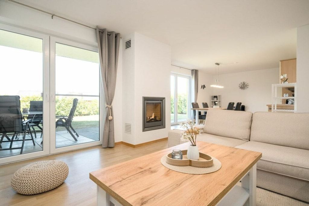 Ein modernes Wohnzimmer mit Kamin, einer Couch, einem Holztisch und einem Essbereich mit Stühlen.