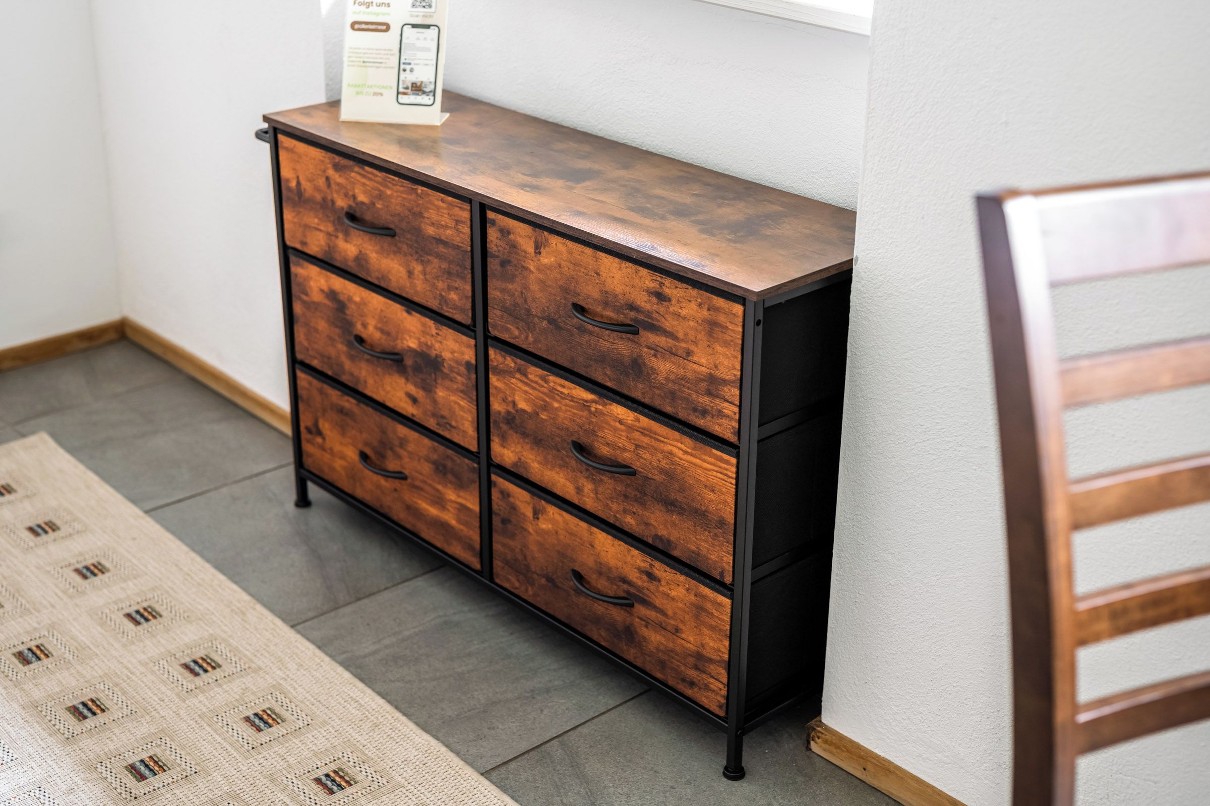 Een houten dressoir met vier lades en een klein bordje erboven.