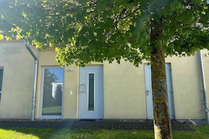 A building with a beige exterior, two doors, and a tree in front. - Lontargos upper floor apartment (Göhren-Lebbin)