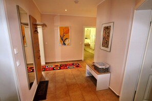 A hallway with a doormat, a bench with a basket, and two framed artworks on the walls. - HOUSE TRAKEHNEN / GROUND FLOOR APARTMENT (Göhren-Lebbin)
