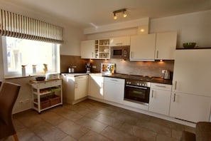 A modern kitchen with white cabinets, a microwave, oven, and a coffee maker. - HOUSE TRAKEHNEN / GROUND FLOOR APARTMENT (Göhren-Lebbin)