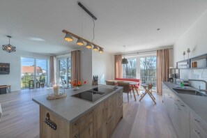 A modern kitchen with a large island, pendant lighting, and a dining area with a view. - Holiday apartment in Göhren-Lebbin with sauna (Göhren-Lebbin)