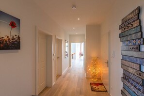 A hallway with a wooden floor, a decorative wall with patterned tiles, and a framed artwork on the left. - Holiday apartment in Göhren-Lebbin with sauna (Göhren-Lebbin)