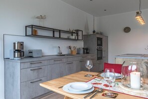 A modern kitchen with grey cabinets, a wooden countertop, and a dining area with a table set for two. - Holiday apartment in Göhren-Lebbin with sauna (Göhren-Lebbin)