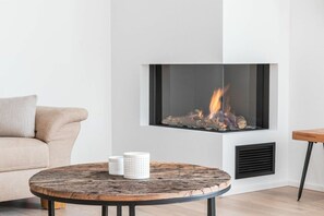 A modern living room with a fireplace, a round wooden table, and a beige sofa. - Holiday apartment in Göhren-Lebbin with sauna (Göhren-Lebbin)