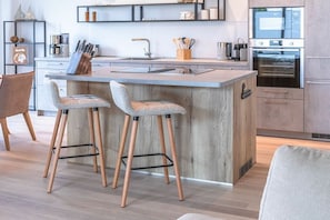 A modern kitchen with a central island, bar stools, and built-in appliances. - Holiday apartment in Göhren-Lebbin with sauna (Göhren-Lebbin)