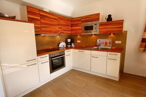 A compact kitchen with white cabinets, a microwave, a coffee maker, and a toaster. - Holiday Home Morning Sun (Göhren-Lebbin)