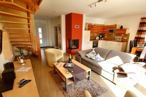 A modern living room with a sofa, a coffee table, and a fireplace. - Holiday Home Morning Sun (Göhren-Lebbin)