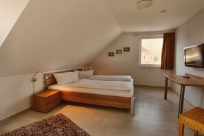 Ein Schlafzimmer mit einem Bett, einem Nachttisch, einer Lampe und einem Fernseher an der Wand.