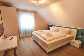 A bedroom with a bed, bedside tables, a desk, and a window with curtains. - Luxury holiday home Limerick (Göhren-Lebbin)