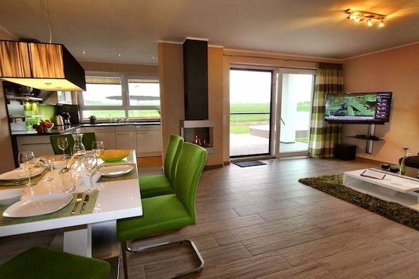 A modern living room with a dining area, a fireplace, a television, and a view of the outdoors. - Luxury holiday home Limerick (Göhren-Lebbin)