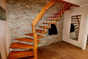 A wooden staircase with a stone wall background. - Luxury holiday home Limerick (Göhren-Lebbin)